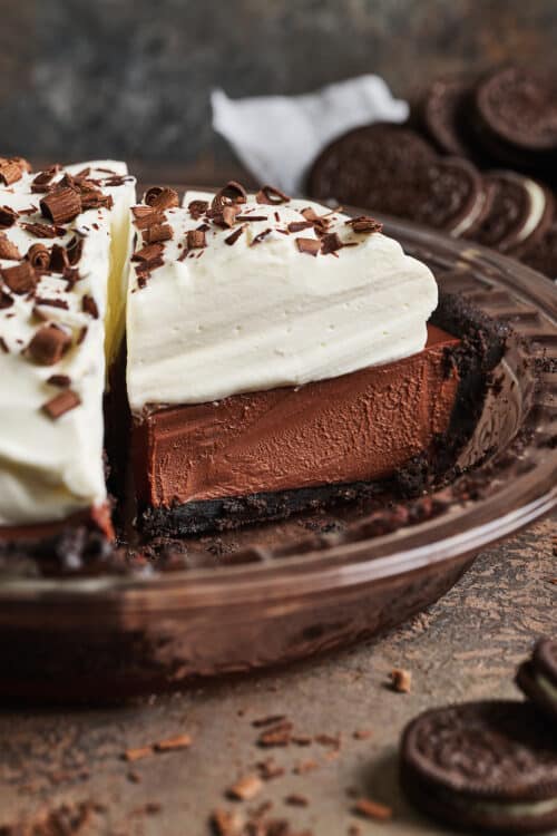 Slice of chocolate cream pie in the baking dish with whipped cream on top.